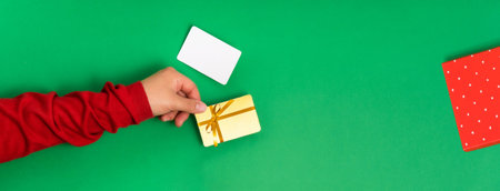 Bonus and gift card template with a bow in female hands on a green backgroundの写真素材