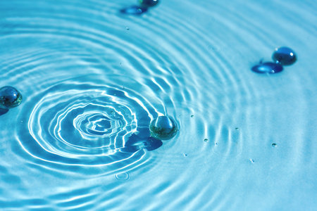 Circles and on the surface of blue water, ripples, water background with granules and collagenの写真素材