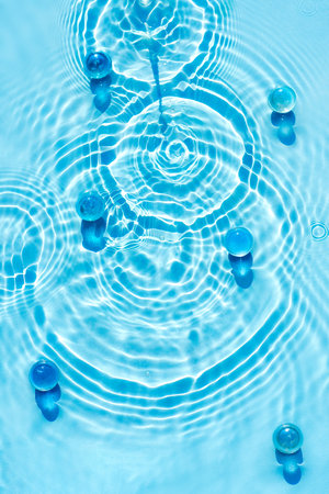 Clear water surface texture in transparent blue color with ripples, splashes and granules.