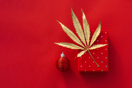 Festive red christmas background with golden marijuana leaf and gift boxの写真素材