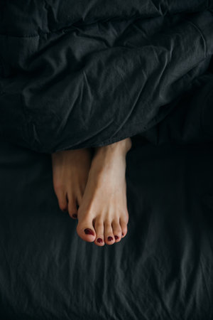 Womens legs stick out from under the covers in bedの写真素材