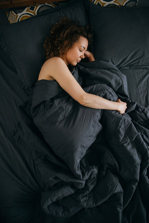 Young woman sleeps in fetal position on an ergonomic bed