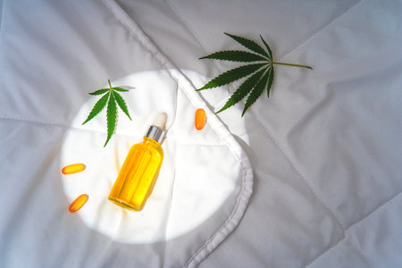 Oil tincture with cannabis in moonlight at night on bed with hemp branchの写真素材
