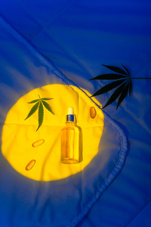 CBD oil tincture and marijuana leaf in night bedroom to improve sleepの写真素材