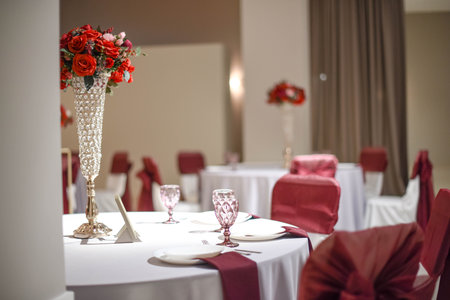 Festive table setting in banquet hall with red bouquetsの写真素材