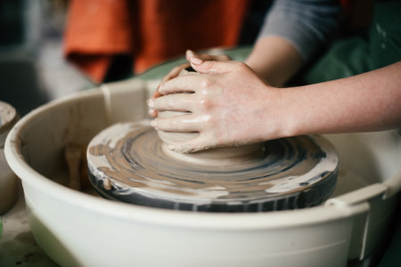 Close-up of a woman hands moulding a ceramic piece on the potters wheel Creating a ceramic mould from clay in potters workshopの写真素材