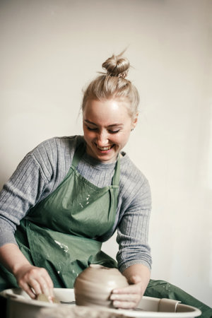 Young woman moulding pottery on the potters wheel . Potter moulding the walls of clay ware on potters wheelの写真素材