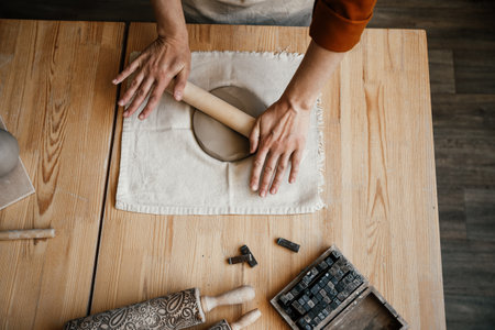 Female potter preparing clay for modelling on a table, top view. Potter kneading and rolling clay, preparing for hand modellingの写真素材