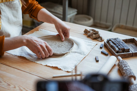 Hand modelling of openwork clay plate, pottery. Womens hands working with clay, close-upの写真素材