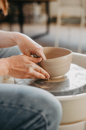 Forming the walls of a clay product on a potters wheel. Pottery, female hands of a potter create a product from white clayの写真素材