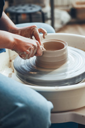 The female hands of a potter model a clay product on a wheel. Pottery craft, shaping a clay product, weekend activityの写真素材