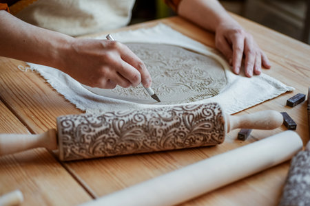 Potter is cutting out the shape of the future plate from the clay layer. Unplugging, hobby