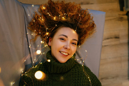 Cozy Christmas and New Year scene with a woman lying on a couch, surrounded by glowing lights....