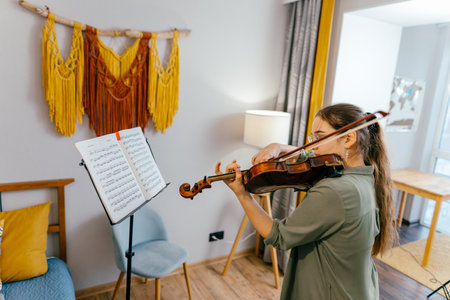 Focused young artist playing violin and studying music composition A dedicated violin student practices classical compositions, focusing on precision and techniqueの写真素材