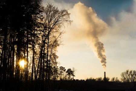 Sunset view of factory emissions polluting the atmosphere. Environmental pollution from factories at sunriseの写真素材