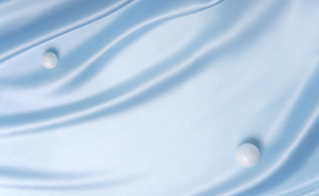 Smooth blue fabric with two white spheres like snowballs. Minimal festive background for Christmas, winter sale or product display.の写真素材