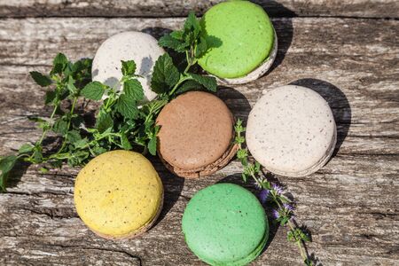 Colorful macaroons with a sprig of mint on a wooden table in the summer gardenの写真素材