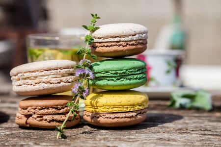 Colorful macaroons with a sprig of mint on a wooden table in the summer gardenの写真素材