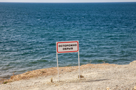 Sign "Caution cliff" at the edge of the cliff in the seaの写真素材