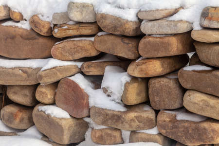 Stacked stones, covered with snow. A wall of stones.の写真素材
