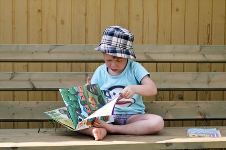 Little redhead boy is reading a book