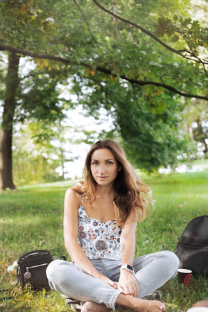 Blonde hair girl are sitting under the tree in lotus pose with district sightの写真素材