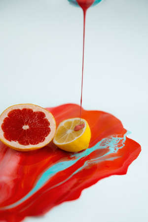 Half of lemon and grapefruit on the color juice with juicy liquid are flowing downの写真素材