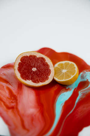 Half of lemon and grapefruit on the color juice with juicy liquid are flowing downの写真素材