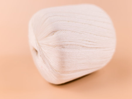 White cotton yarn cone on neutral background, minimal handmade knitting and crochet supplies concept