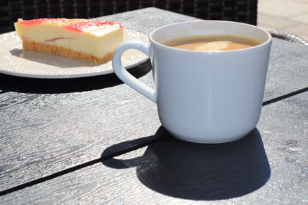 The view on the cup of coffee and place of cake served on the tableの写真素材