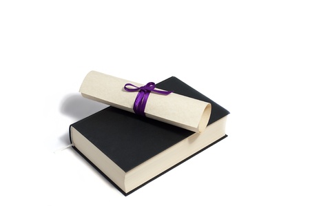 diploma with purple bow on black book isolated on whiteの写真素材