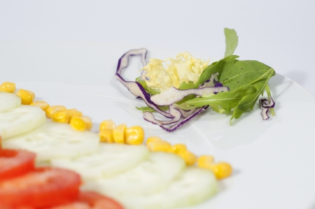 dish with sliced tomatoes, and cucumbers, with corn, isolated on white backgroundの写真素材