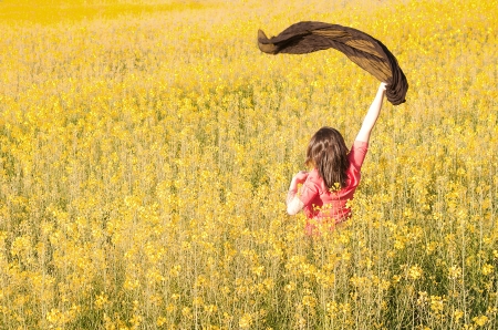 Girl holding a scarf in a rapeseed fieldの写真素材
