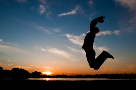 silhouette of a man jumping in the sunsetの写真素材
