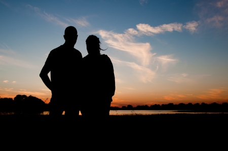 silhouette of a young couple jumping in the sunsetの写真素材