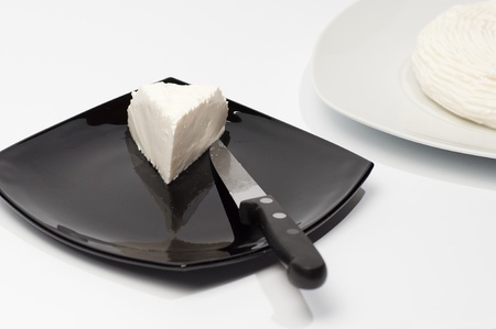 cheese on a white plate with a portion cut in an other plateの写真素材