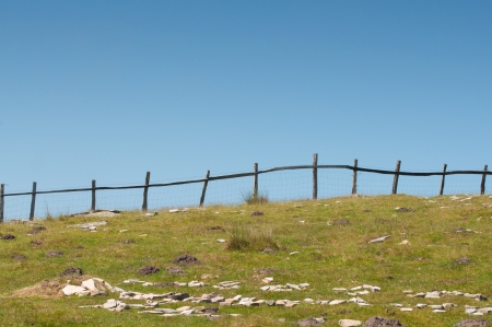 grass field fenced, and blue skyの写真素材