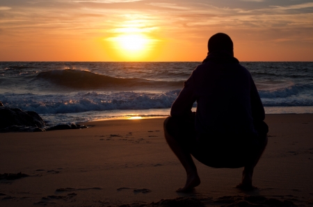 Man looking to the horizon at the beach, at sunsetの写真素材