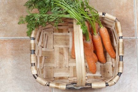 Bunch of carrots on a basket, on a tile backgroundの写真素材