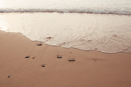 Little stones in the beach sand and waves comingの写真素材