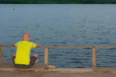 Young man sitting in the lake shore at sunsetの写真素材