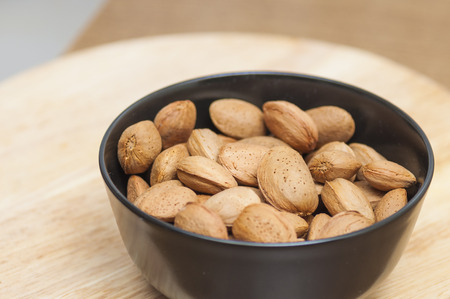 Almonds on a black bowl on wooden 