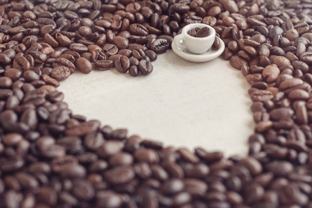 Coffee beans shaped heart and toy cup with coffee, conceptの写真素材