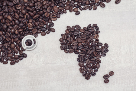 Coffee beans shaped Africa and toy cup with coffee, conceptの写真素材