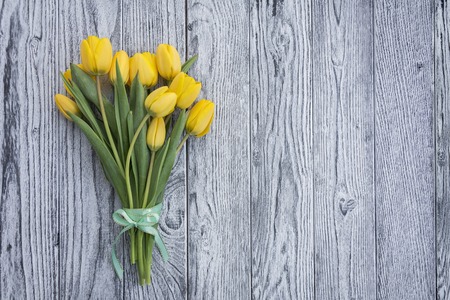 Yellow tulips with ribbon on wooden background. Top view with copy spaceの写真素材