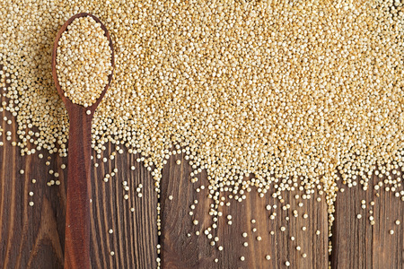 Kinoa seeds in wooden spoons on wooden table, top view, organic foodの写真素材