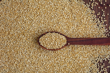 Kinoa seeds in wooden spoons on wooden table, top view, organic foodの写真素材