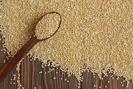 Kinoa seeds in wooden spoons on wooden table, top view, organic foodの写真素材
