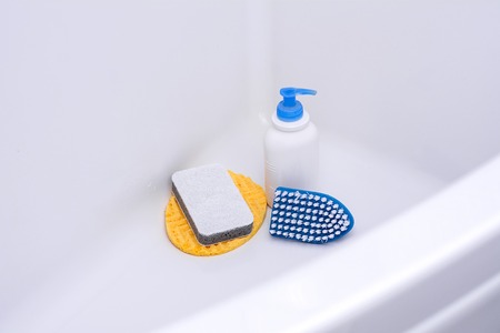 Brush, washcloth and rubber gloves in white bath. Things for cleaning. All in light blue on a white background.の写真素材