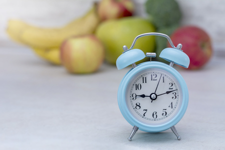 Blue alarm clock in morning light and and fruits on table, morning conceptの写真素材